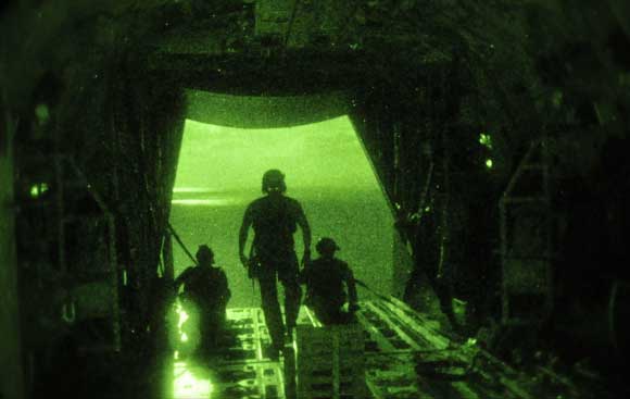 Night vision view of soldiers exiting the rear of a transport